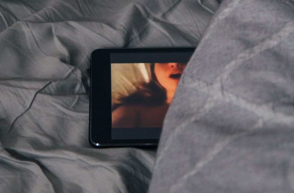 Screen showing porn hidden in duvet